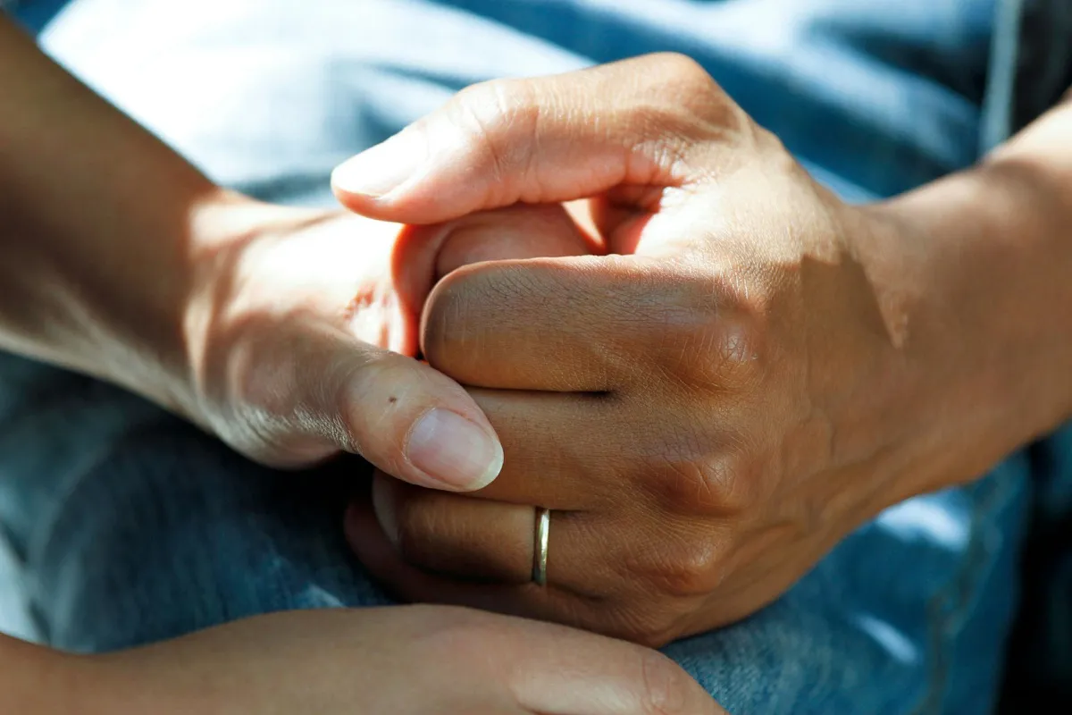 Caring hands holding elderly person's hand
